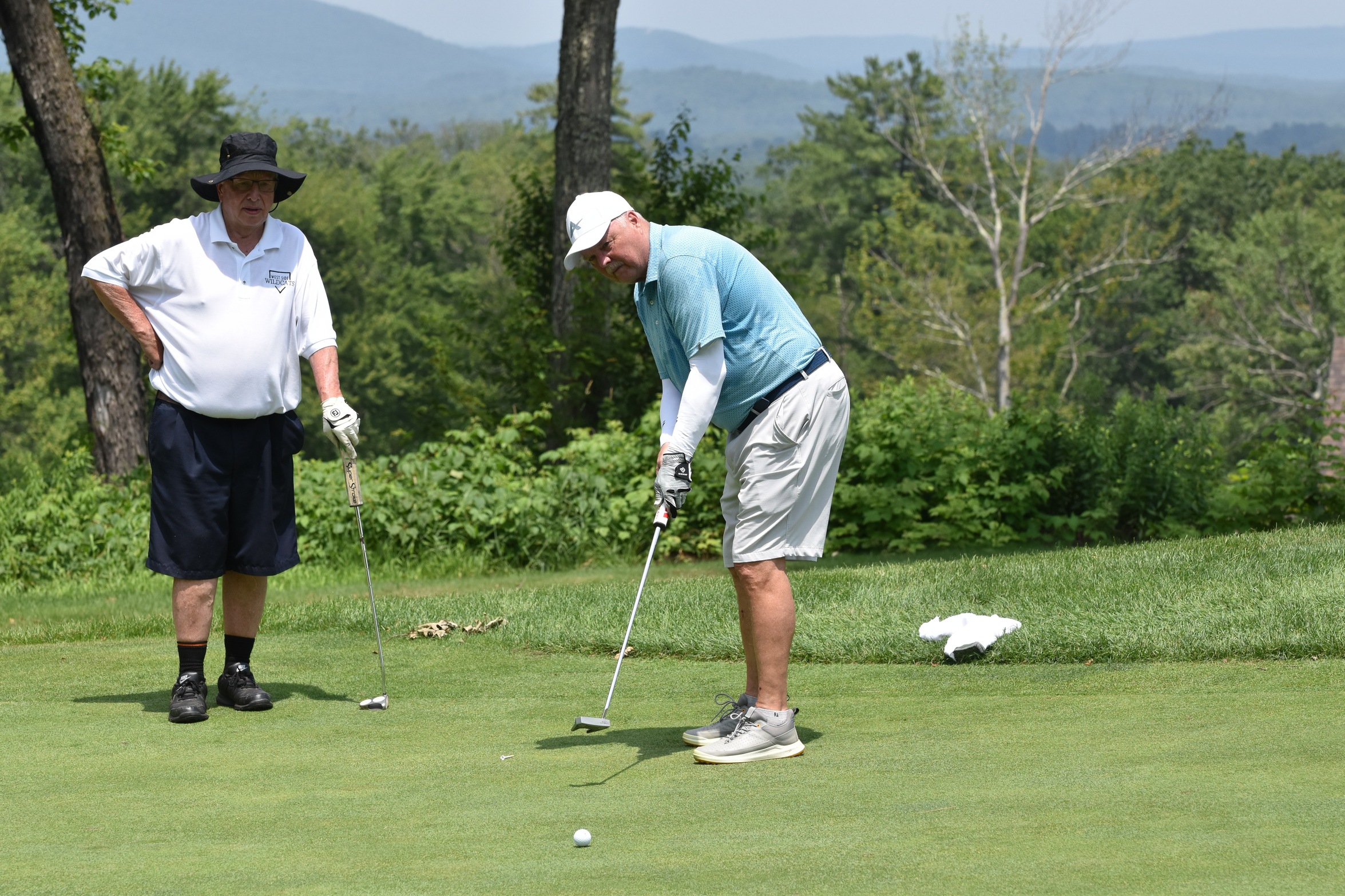 Greg Little putts as Tom Tierney looks on in the 2025 Owl Club Golf Tournament.